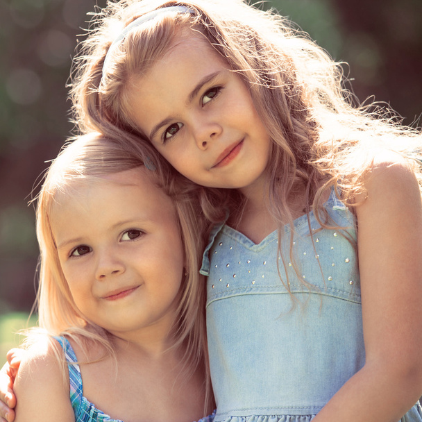 Outdoor portrait of two embracing cute little girls - Φωτογραφία, εικόνα