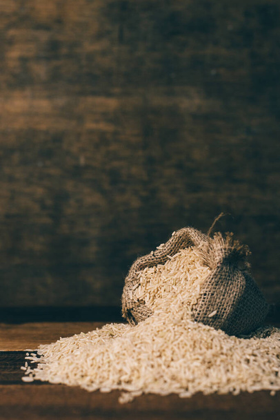 imagen vertical de arroz integral natural en saco de arpillera sobre mesa de madera. comida saludable y concepto de alimentación - Foto, Imagen