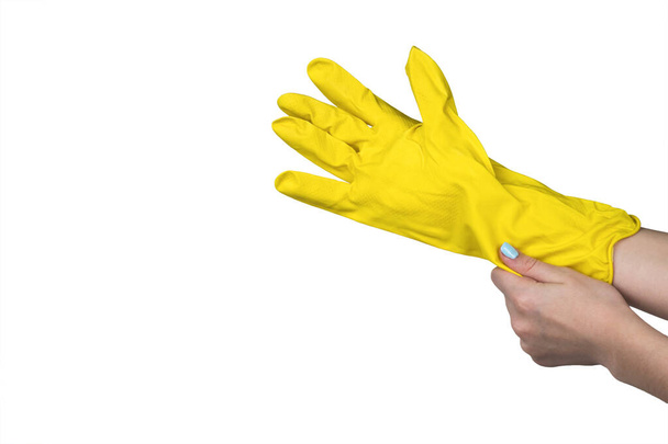 Die Hände der Frauen tragen gelbe Gummihandschuhe auf weißem Hintergrund. Schutzvorrichtung für die Heimarbeit. - Foto, Bild