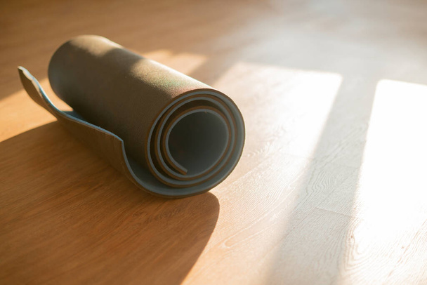 a roll of yoga mat on the wooden floor, doing exercise in the gym, sport equipment - Fotoğraf, Görsel