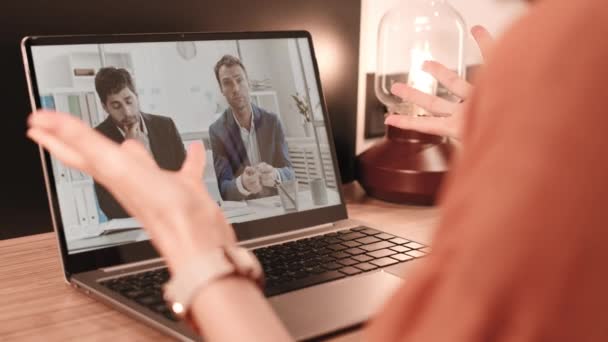 Přes rameno nerozpoznatelné osoby sledující přenosnou obrazovku počítače s běžícím videem dvou různých podnikatelů mluvících - Záběry, video
