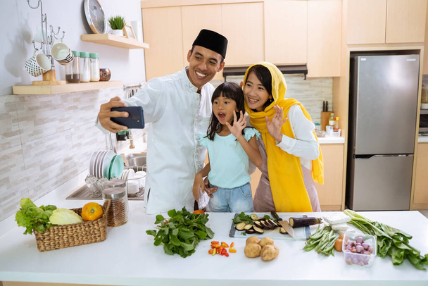 muslim family making a video, selfie or a phone call together during iftar dinner preparation - Фото, изображение