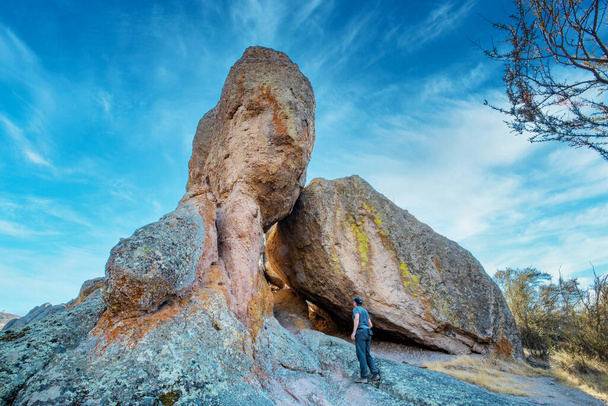 San Benito County en Monterey County, Californië, Verenigde Staten - 10 oktober 2020, een toerist in de buurt van een grote rots, in Pinnacles National Park. Concept, actieve recreatie in de natuur, toerisme. - Foto, afbeelding
