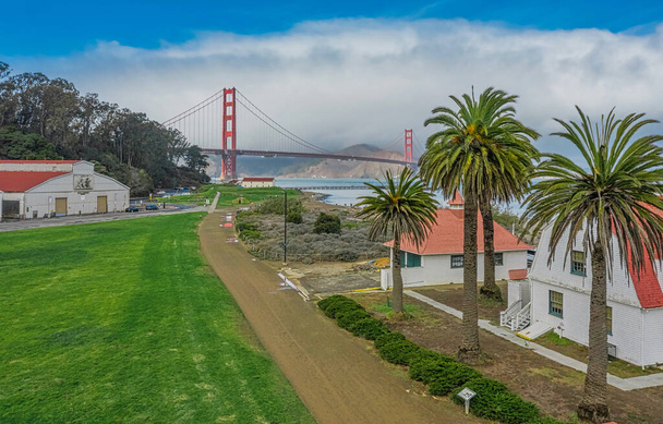 Luchtfoto van de Golden Gate Bridge vanuit Presidio, tegen de achtergrond van prachtige palmbomen, in San Francisco, zonnig weer, palmbomen en groen gras op het gazon. - Foto, afbeelding