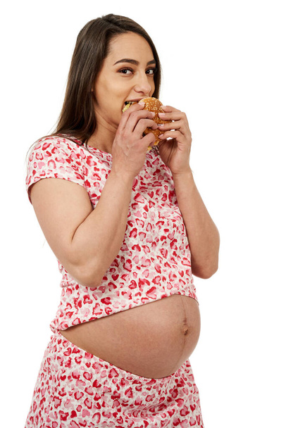 Pregnant woman craving a hamburger, portrait isolated on white background - Foto, Bild