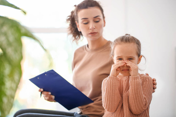 Vrouwelijke psycholoog werkt met triest klein meisje in het kantoor - Foto, afbeelding