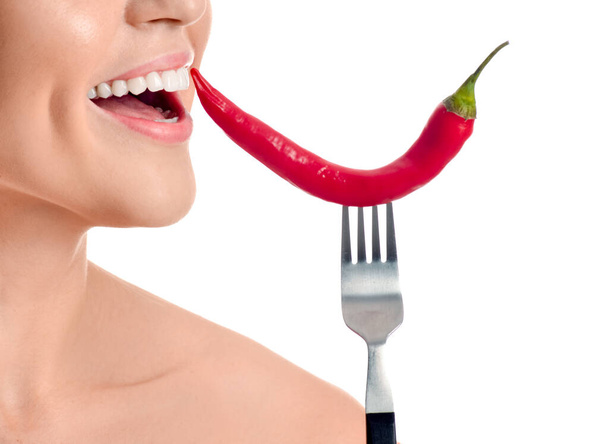 Beautiful young woman with chili pepper on white background - Photo, Image