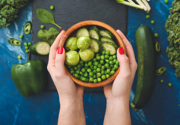 Žena ruce s miskou zelené zeleniny na barevném pozadí, detailní záběr - Fotografie, Obrázek