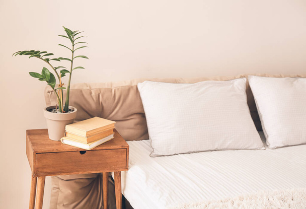 Wooden table with houseplant and books in bedroom - Fotoğraf, Görsel