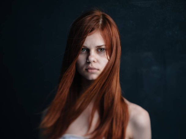 Πορτρέτο μιας γυναίκας με κόκκινα μαλλιά σε μαύρο φόντο  - Φωτογραφία, εικόνα