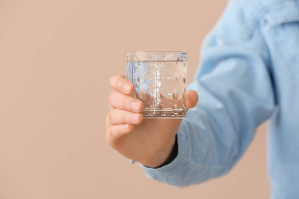 Vrouwelijke hand met glas water op kleur achtergrond - Foto, afbeelding