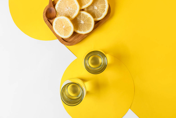 Glazen van water en citroenen op kleur achtergrond - Foto, afbeelding