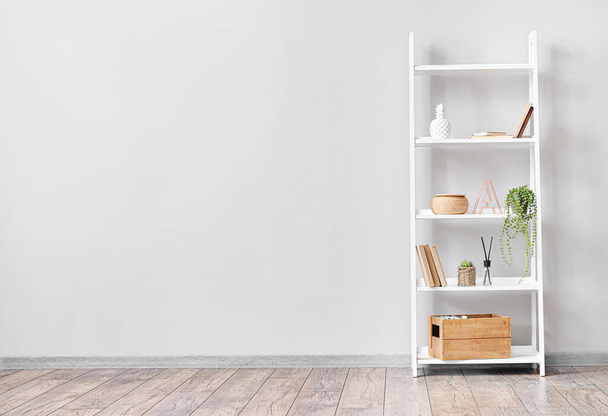 Modern shelf unit with decor near light wall in room - Фото, изображение