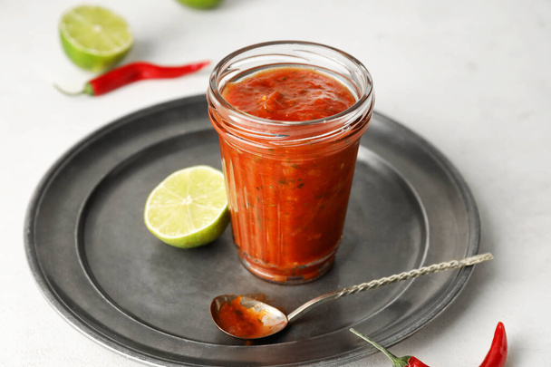 Γυάλινο βάζο με νόστιμη σάλτσα salsa με συστατικά σε ελαφρύ φόντο - Φωτογραφία, εικόνα
