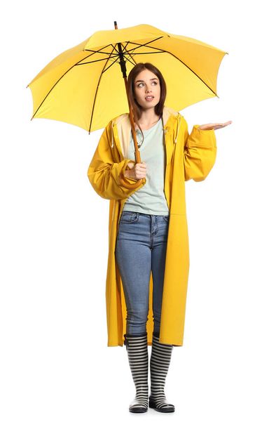 Stylish young woman in raincoat and with umbrella on white background - Zdjęcie, obraz