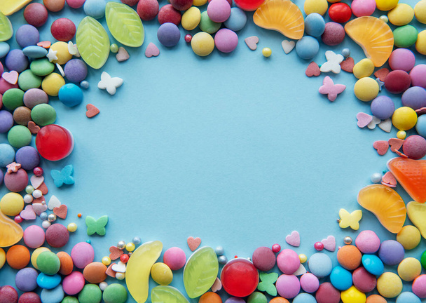 Kleurrijke snoepjes, gelei en marmelade op blauwe achtergrond met ruimte voor tekst - Foto, afbeelding