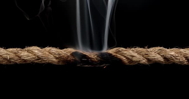 Rope stretched tight and slowly burning apart, finally snapping in two. Concept of dangerous stress or stressful situation like divorce separation, deadlines, failure, or tension. - Footage, Video