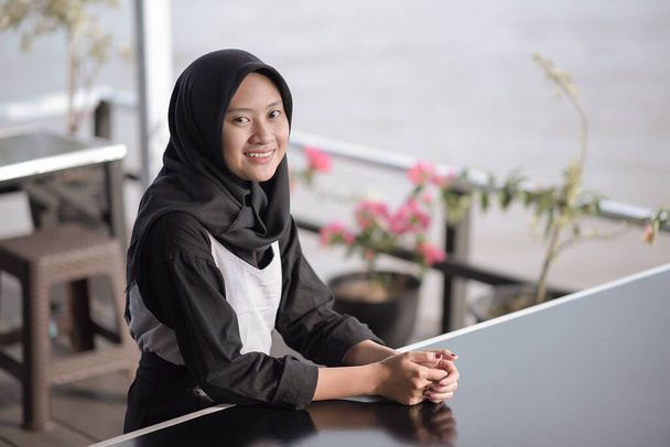 Portrait image of a beautiful young Muslim asian woman sitting in cafe with feeling happy - Foto, imagen