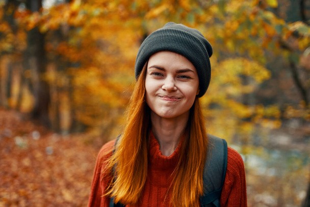 retrato de uma mulher bonita em um chapéu e suéter com uma mochila na floresta de outono na natureza. Foto de alta qualidade - Foto, Imagem