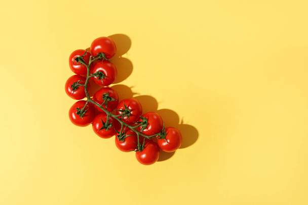 Świeże pomidory wiśniowe z cieniem na żółtym tle. - Zdjęcie, obraz