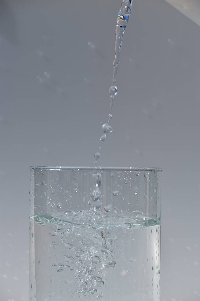 A vertical shot of water pouring into a glass jar - Fotografie, Obrázek
