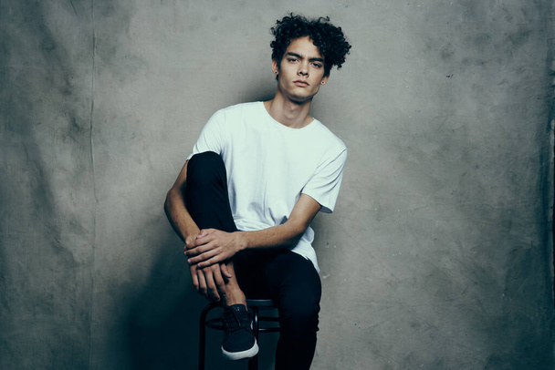 man with curly hair sitting on a chair in fashion studio. High quality photo - Photo, Image