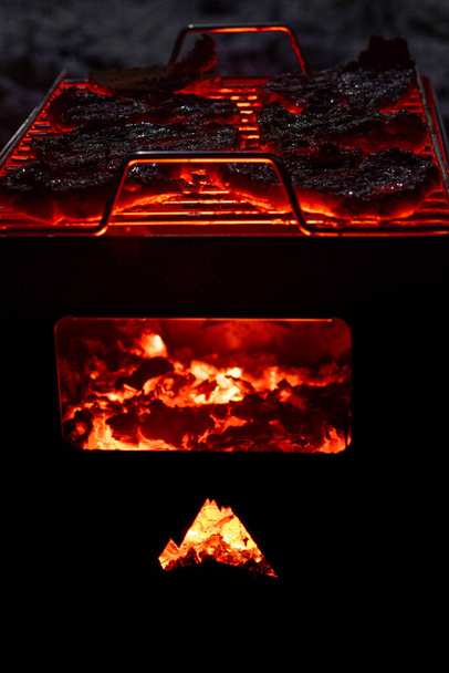 A vertical shot of meat on a burning grill with wood - Foto, afbeelding