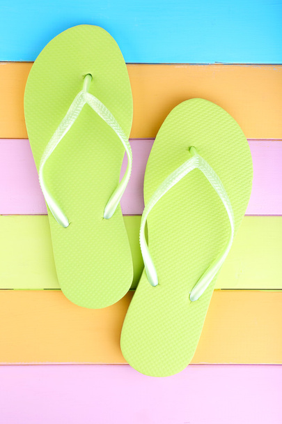 Bright flip-flops on color wooden background - Фото, зображення