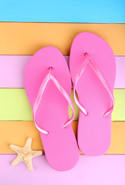 Bright flip-flops on color wooden background - Foto, imagen