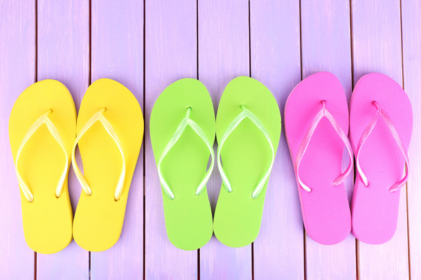 Bright flip-flops on color wooden background - Foto, Bild