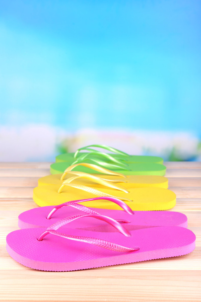 Bright flip-flops on wooden table, on nature background - Fotografie, Obrázek