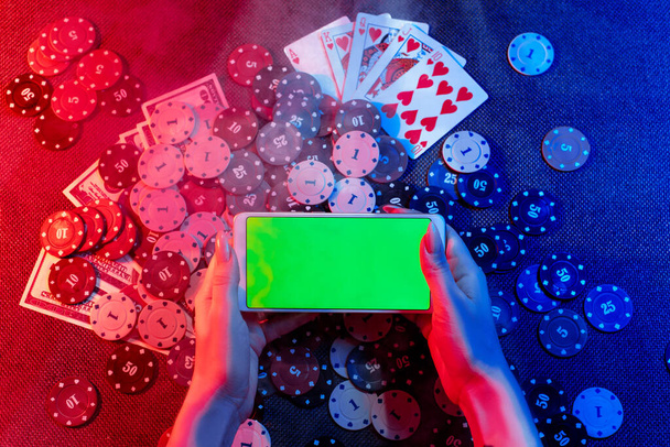 Koncept online kasina: hrací karty, sázení žetony a smartphone s kopií prostoru v dámských rukou. Horní pohled. Kouř přidán na fotografii - Fotografie, Obrázek