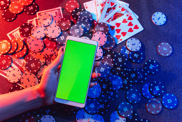 Концепция онлайн-казино: игральные карты, фишки для ставок и смартфон с копировальным пространством в женских руках. Вид сверху. - Фото, изображение