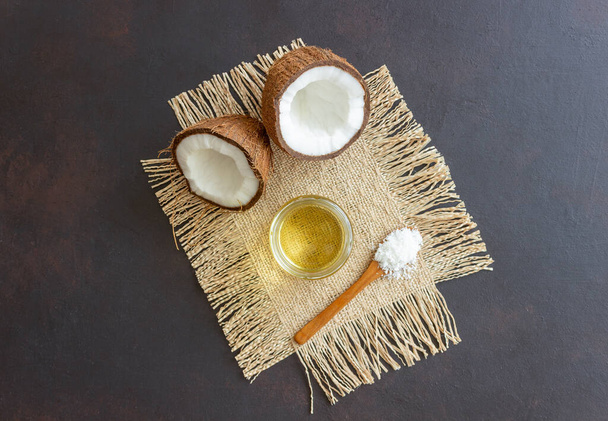 Coconut oil in a jar and fresh coconuts on a beige background. Natural cosmetics - Photo, Image