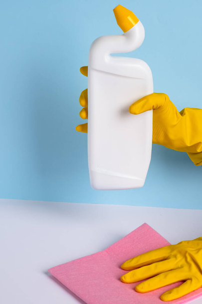 Ženská ruka ve žluté gumové rukavici drží prostředky pro dezinfekci záchodové mísy. Čistota a hygiena v domě. Kvalitní fotografie - Fotografie, Obrázek