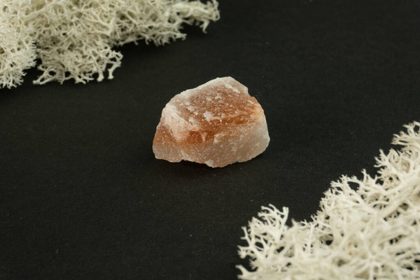 Халит или каменная соль из Пакистана. Природный минеральный камень на черном фоне в окружении мха. Минералогия, геология, магия, полудрагоценные камни и образцы минералов. Макрофото крупным планом. - Фото, изображение