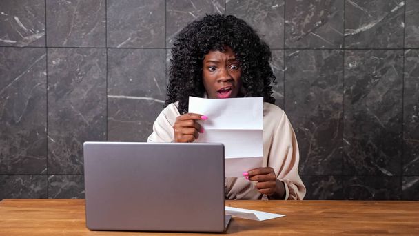 Schwarze Geschäftsfrau öffnet Umschlag mit Brief schockiert - Foto, Bild
