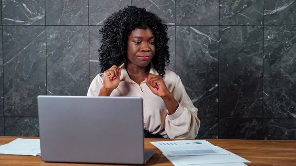 Задумчивая черная деловая женщина смотрит вокруг, держа ручку - Фото, изображение