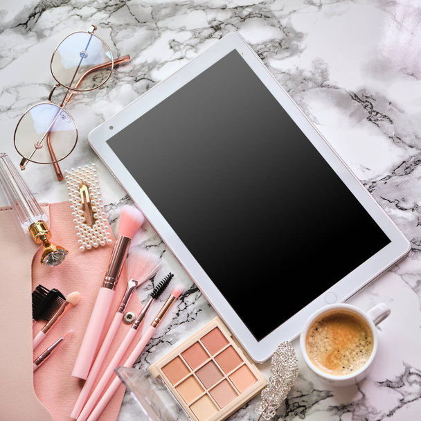Плоска композиція з планшетами та косметичними засобами, кавою та окулярами для жінки на мармуровому столі
 - Фото, зображення