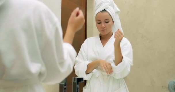 Donna con asciugamano morbido sulla testa lava viso in bagno - Filmati, video