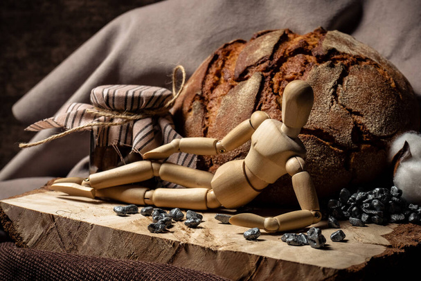 The mannequin for drawing lies on a wooden board next to bread and a jar of biscuits on a brown background - Fotoğraf, Görsel