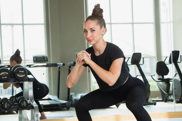 Belle femme caucasien blanc genou flexion exercice yoga dans fitness gymnase arrière-plan équipement d'exercice - Photo, image