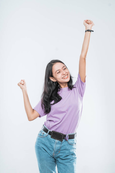 Asian young girl smiling happy while clenched into fists and raised two hands - Foto, Imagen