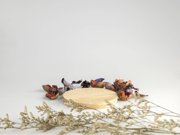 Wooden stand with dried flowers and various dried fruit bark on white background. For placing products for advertising purposes. - Photo, Image