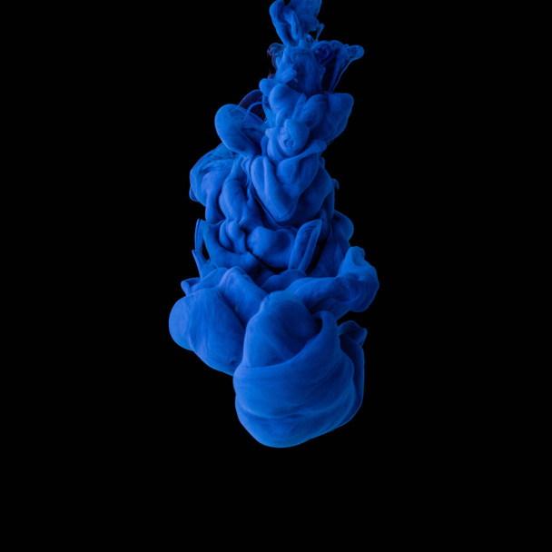 Explosion of colored, fluid and neoned liquids on black studio background with copyspace - Photo, Image