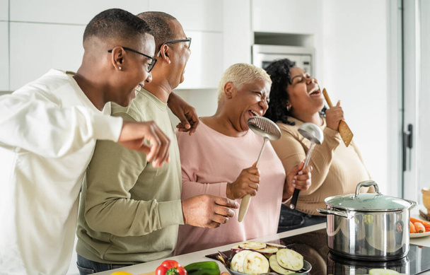 Счастливая чернокожая семья с удовольствием готовит вместе на современной кухне - Еда и концепция единства родителей - Фото, изображение