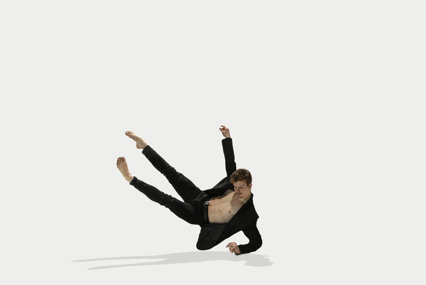 Man in casual style clothes jumping and dancing isolated on white background. Art, motion, action, flexibility, inspiration concept. Flexible caucasian ballet dancer. - Fotó, kép