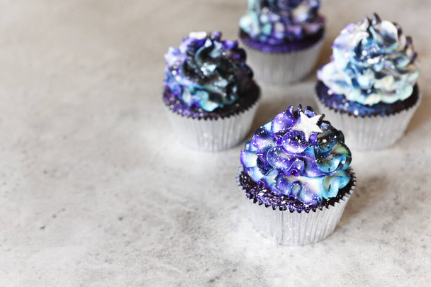 Haut angle de délicieux cupcakes à la crème colorée galaxie et décoration en forme d'étoile placés sur une table grise - Photo, image