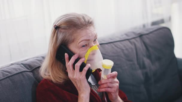 Starší žena používající kyslíkový inhalátor, když telefonuje. Ohnisko koronaviru a zranitelná skupina lidí - Záběry, video