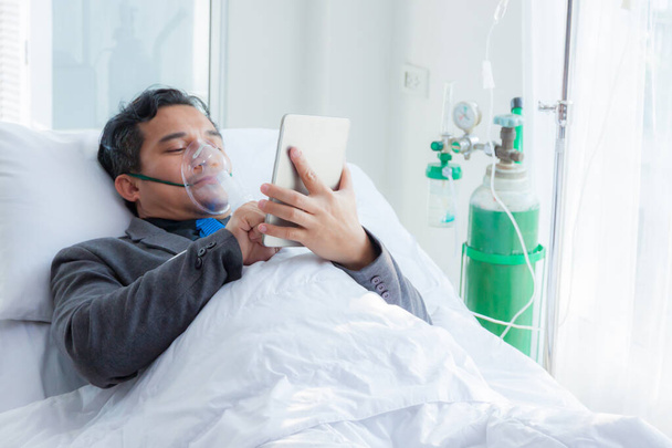 Больной человек. Бизнесмен, работающий на больничной койке с солевым раствором для пациентов - Фото, изображение